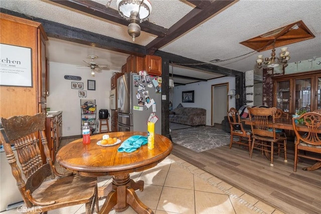 dining space with ceiling fan, beamed ceiling, a textured ceiling, and light hardwood / wood-style floors