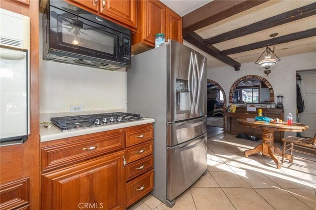 kitchen with light tile patterned floors, pendant lighting, appliances with stainless steel finishes, and beamed ceiling