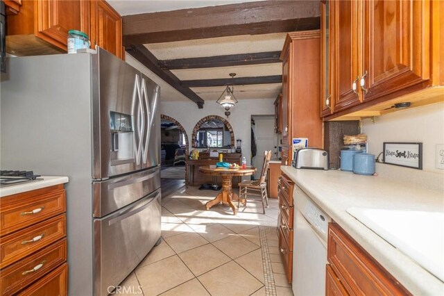 kitchen featuring decorative light fixtures, beamed ceiling, stainless steel fridge, white dishwasher, and light tile patterned floors