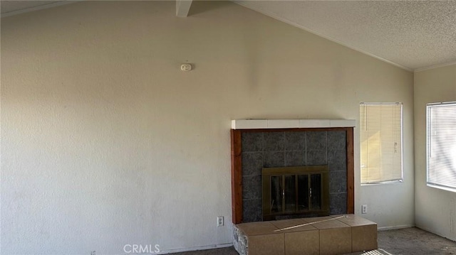 unfurnished living room featuring lofted ceiling, carpet, a tile fireplace, and a textured ceiling