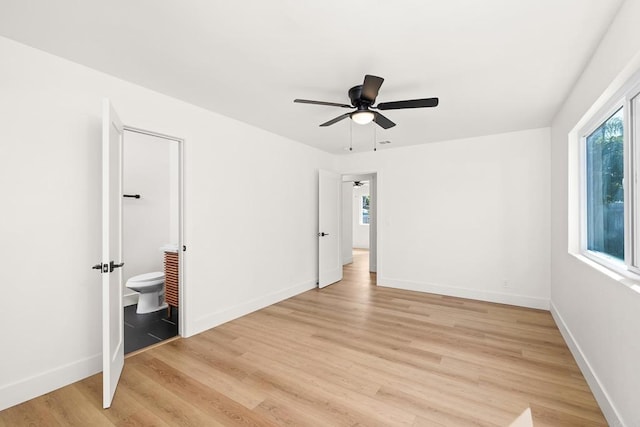 unfurnished bedroom featuring ensuite bath, ceiling fan, and light wood-type flooring