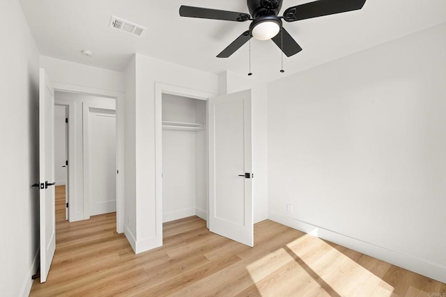 unfurnished bedroom featuring light wood-type flooring, ceiling fan, and a closet