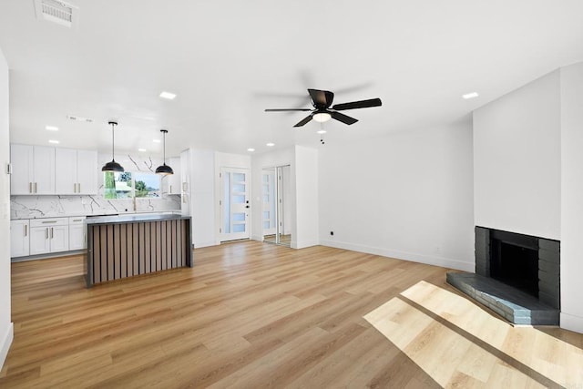 living room featuring ceiling fan, a fireplace, and light hardwood / wood-style floors