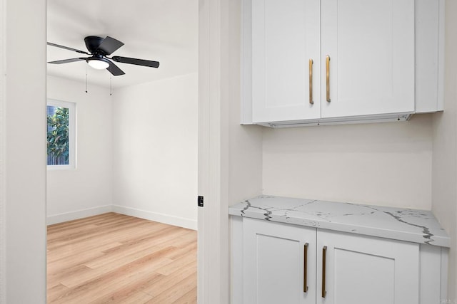 interior space featuring ceiling fan, light stone countertops, white cabinets, and light hardwood / wood-style floors