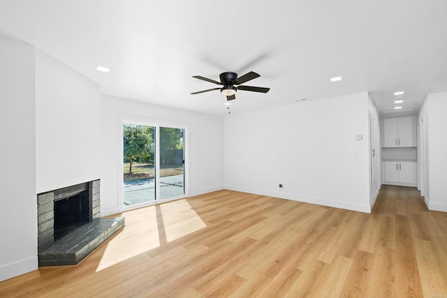 unfurnished living room featuring a brick fireplace, light hardwood / wood-style flooring, and ceiling fan