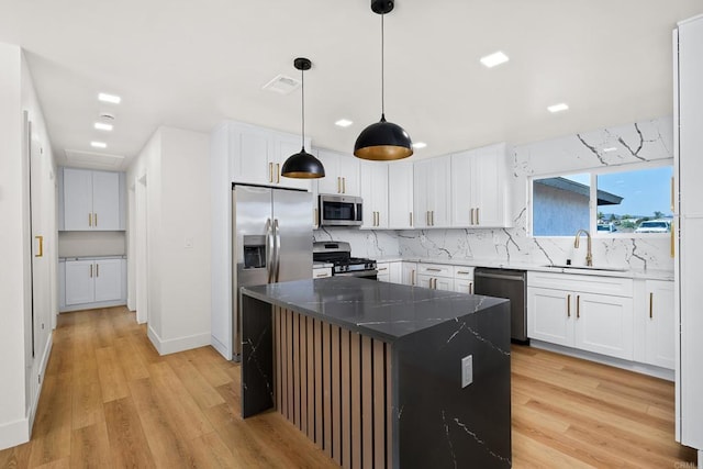 kitchen featuring stainless steel appliances, a center island, white cabinetry, and sink