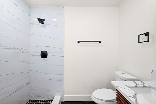 bathroom featuring toilet, tiled shower, and vanity