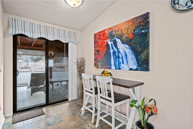 dining area with a textured ceiling and vaulted ceiling