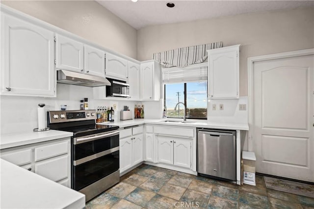 kitchen featuring sink, white cabinetry, stainless steel appliances, and vaulted ceiling