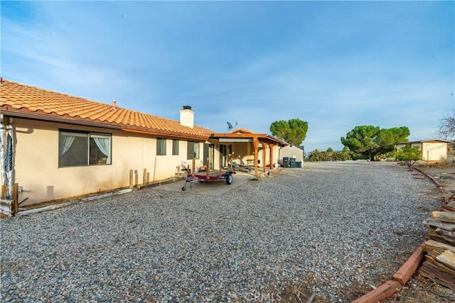 back of property with a storage unit and a patio