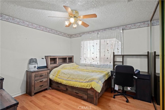 bedroom featuring ceiling fan, a textured ceiling, and light hardwood / wood-style floors