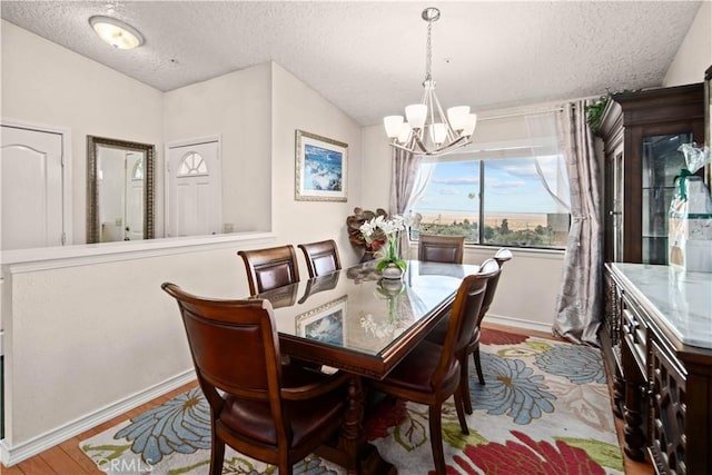 dining area featuring light hardwood / wood-style floors, a textured ceiling, and an inviting chandelier