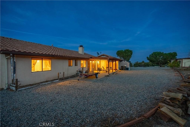 back house at dusk with a patio area