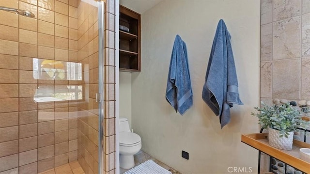 bathroom with a shower with shower door and toilet