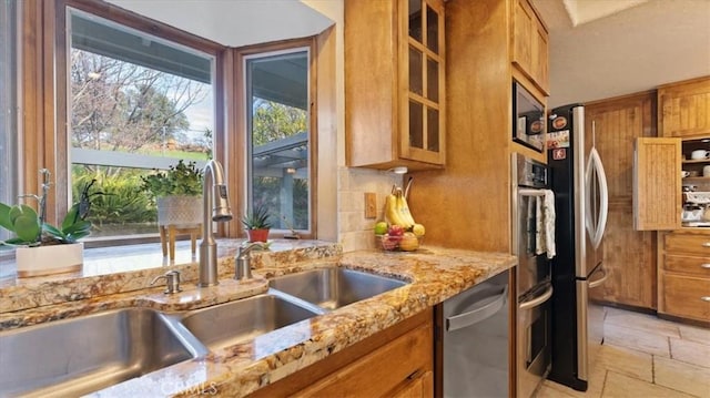 kitchen with stainless steel appliances, light stone counters, and sink