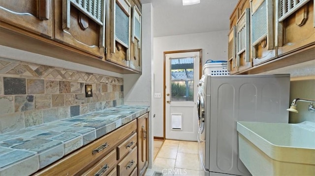 laundry area featuring light tile patterned floors, sink, washer / dryer, and cabinets