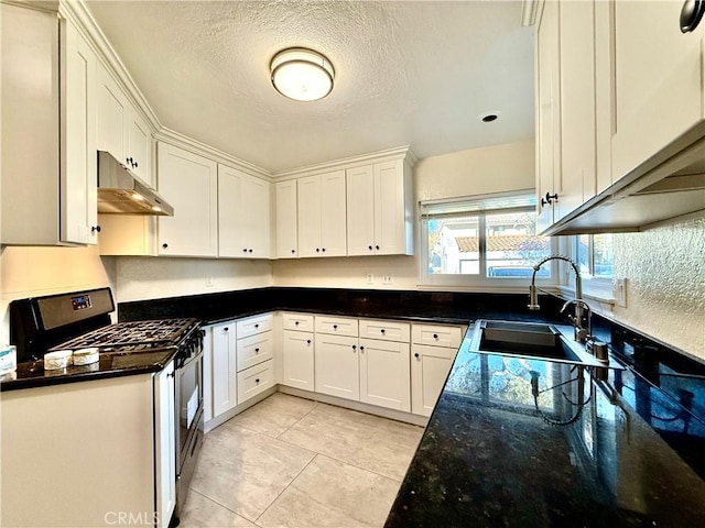 kitchen with sink, white cabinets, dark stone counters, and gas stove