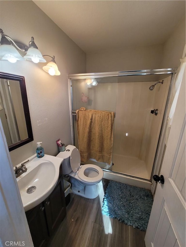 bathroom with wood-type flooring, toilet, an enclosed shower, and vanity