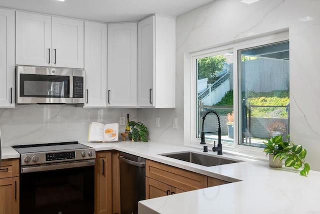 kitchen with backsplash, sink, white cabinetry, and appliances with stainless steel finishes