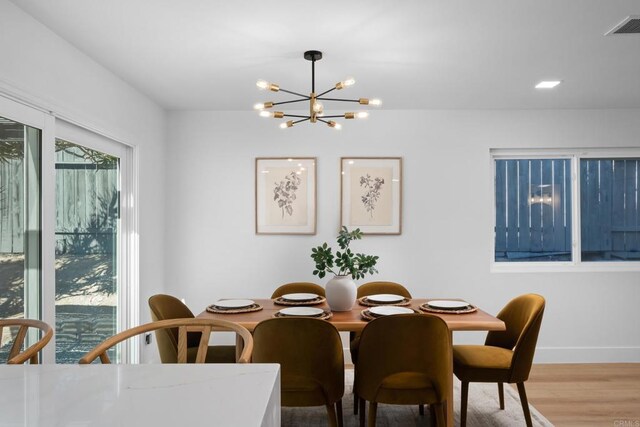 dining area with hardwood / wood-style floors and a notable chandelier