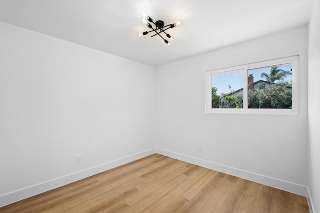 spare room with an inviting chandelier and light hardwood / wood-style flooring