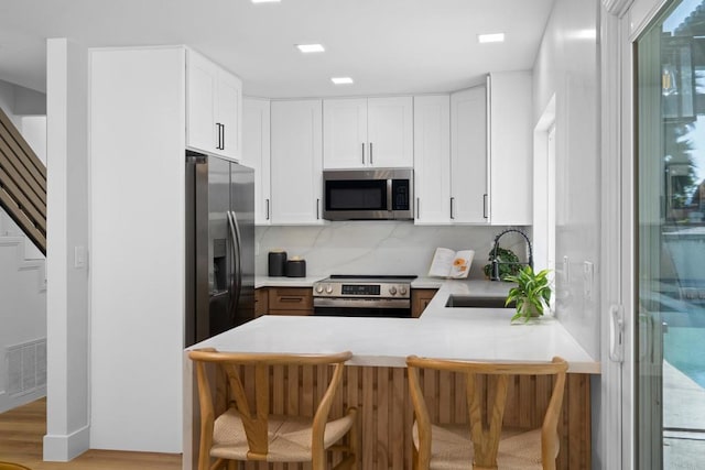 kitchen featuring white cabinets, kitchen peninsula, appliances with stainless steel finishes, and sink