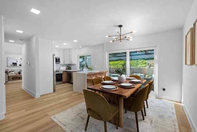 dining area featuring light hardwood / wood-style floors, sink, a wealth of natural light, and a chandelier