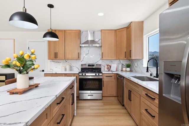 kitchen with sink, wall chimney exhaust hood, decorative backsplash, pendant lighting, and appliances with stainless steel finishes