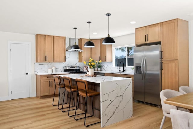 kitchen featuring wall chimney exhaust hood, pendant lighting, a kitchen island, appliances with stainless steel finishes, and sink