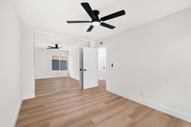 unfurnished bedroom featuring ceiling fan, light wood-type flooring, and a closet