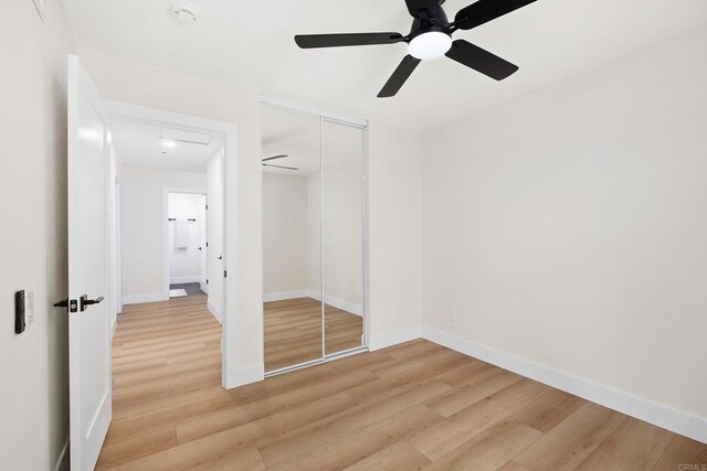 unfurnished bedroom with ceiling fan, a closet, and wood-type flooring