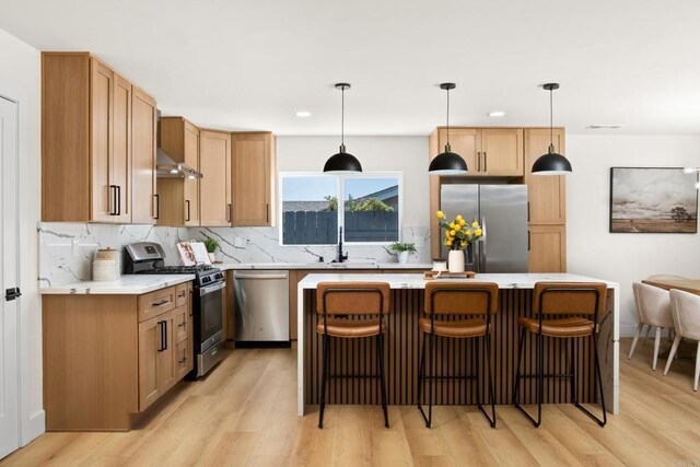 kitchen with decorative light fixtures, backsplash, appliances with stainless steel finishes, and light hardwood / wood-style flooring