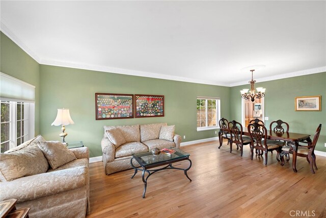 living room with light wood-type flooring, crown molding, and a notable chandelier