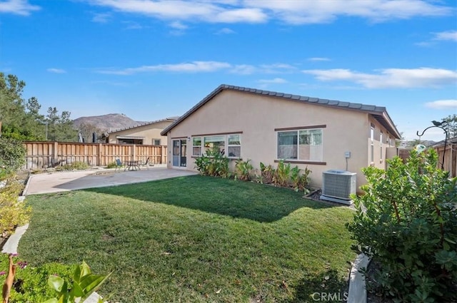 rear view of house featuring stucco siding, central AC, a patio area, a mountain view, and a fenced backyard