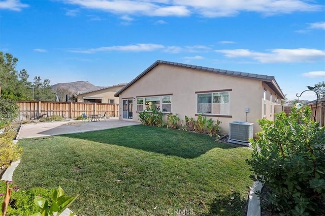 back of house with a patio, a fenced backyard, central AC, stucco siding, and a lawn