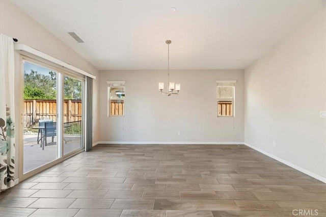 spare room with baseboards, wood tiled floor, visible vents, and a notable chandelier