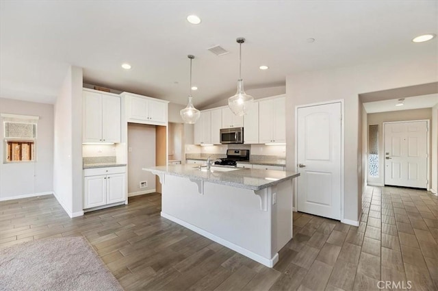 kitchen with visible vents, wood finish floors, light stone counters, appliances with stainless steel finishes, and white cabinetry