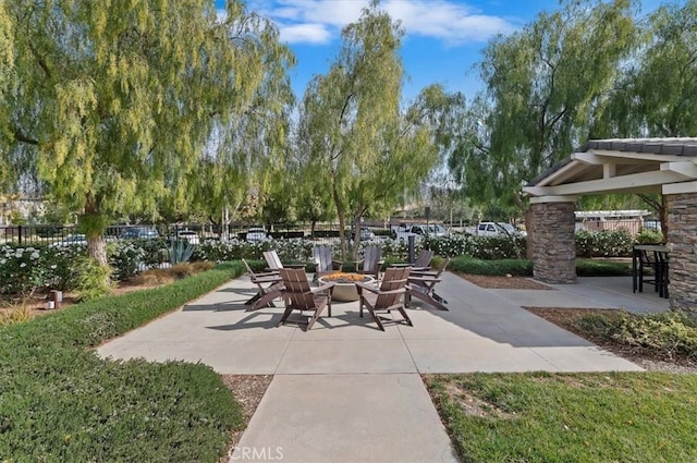 view of property's community with fence, an outdoor fire pit, and a patio area