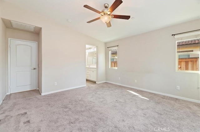 unfurnished bedroom featuring baseboards, visible vents, vaulted ceiling, ensuite bathroom, and light carpet