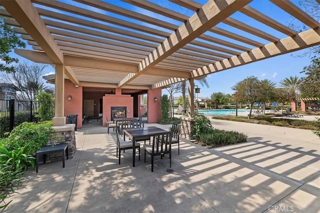 view of patio / terrace with a large fireplace, fence, a community pool, and a pergola