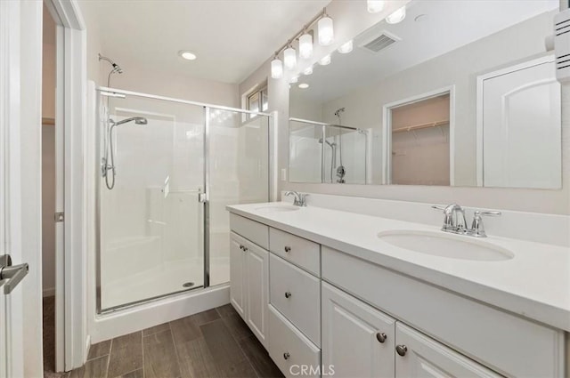 bathroom with double vanity, visible vents, a stall shower, and a sink