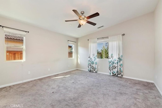 carpeted empty room with vaulted ceiling, baseboards, visible vents, and ceiling fan