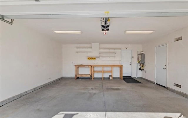 garage featuring baseboards, water heater, and a garage door opener