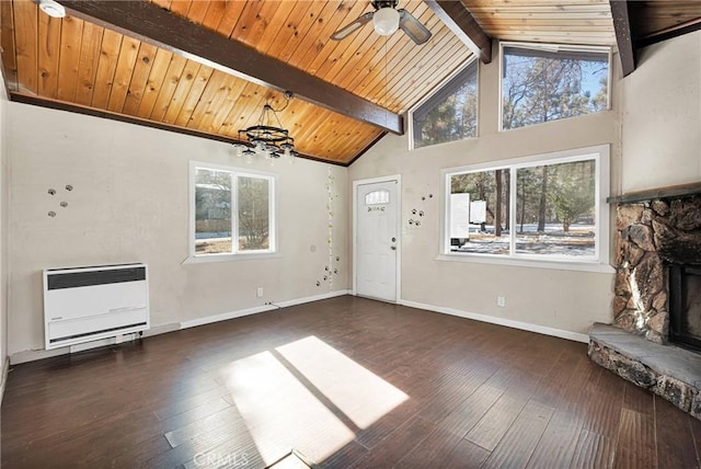 unfurnished living room featuring beam ceiling, heating unit, a stone fireplace, and dark hardwood / wood-style floors