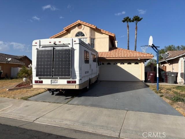 view of front of home with an attached garage, central air condition unit, a tiled roof, driveway, and roof mounted solar panels