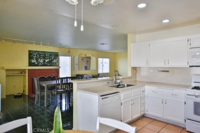 kitchen with white cabinets, a sink, light tile patterned flooring, white appliances, and a peninsula