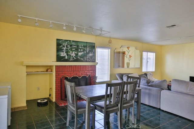 dining space with dark tile patterned flooring, visible vents, and a fireplace