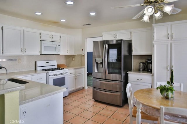 kitchen featuring light tile patterned floors, visible vents, white cabinetry, a sink, and white appliances