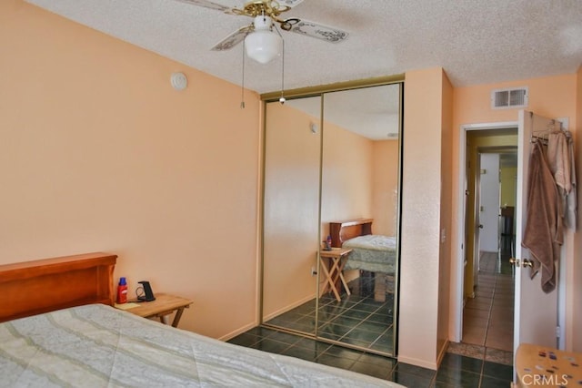 bedroom featuring a closet, visible vents, a textured ceiling, and dark tile patterned flooring