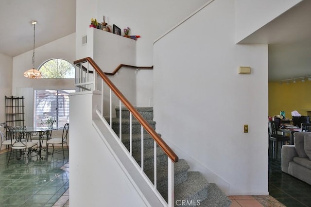 staircase featuring high vaulted ceiling, tile patterned flooring, visible vents, and an inviting chandelier